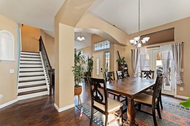 dining room with baseboards, arched walkways, stairway, wood finished floors, and a chandelier