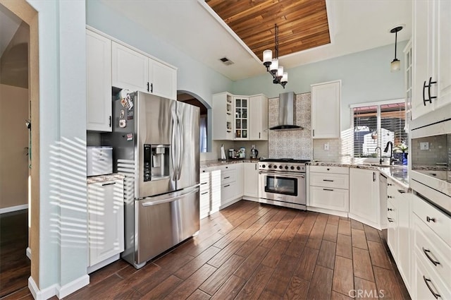 kitchen featuring appliances with stainless steel finishes, dark wood-type flooring, wall chimney range hood, and tasteful backsplash