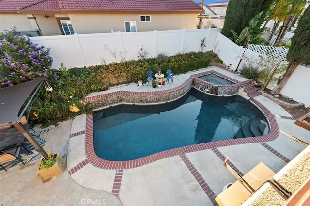 view of swimming pool featuring a patio area, a fenced backyard, and a pool with connected hot tub