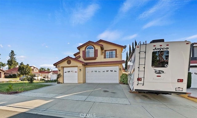 view of front facade with an attached garage, a tiled roof, concrete driveway, and stucco siding