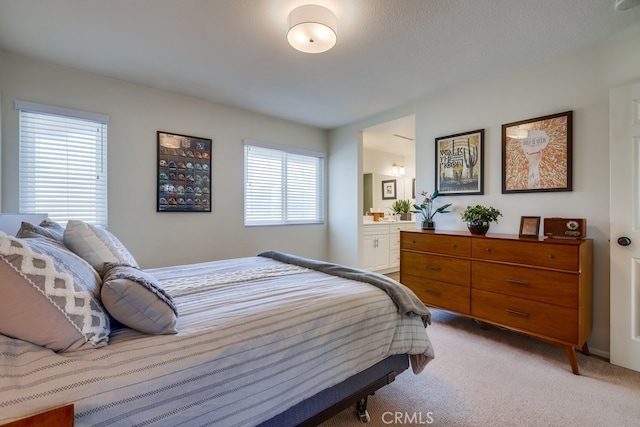 bedroom with light carpet and ensuite bath