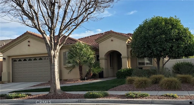 mediterranean / spanish-style house featuring a garage, concrete driveway, a tiled roof, and stucco siding