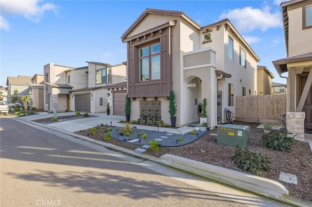 view of front of house featuring driveway, a residential view, an attached garage, fence, and stucco siding