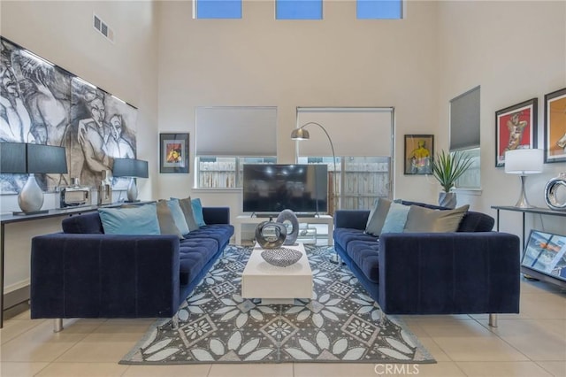 tiled living area with visible vents and a high ceiling