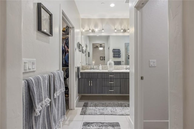 full bath featuring tile patterned flooring, a sink, a ceiling fan, a spacious closet, and double vanity