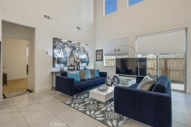 tiled living room featuring baseboards, a high ceiling, and visible vents