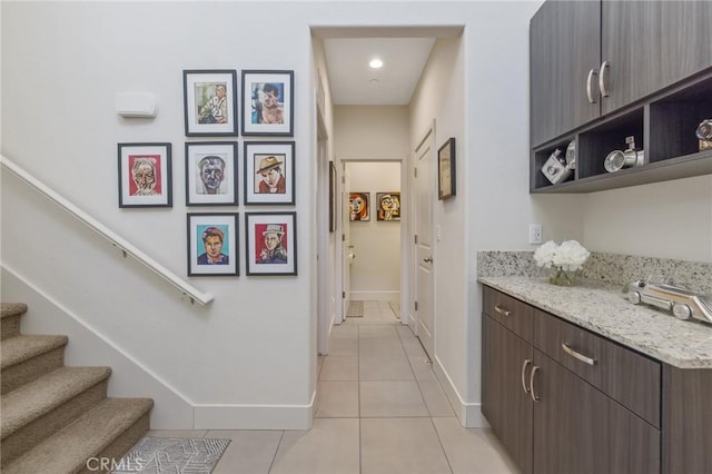 corridor with light tile patterned floors, stairway, and baseboards