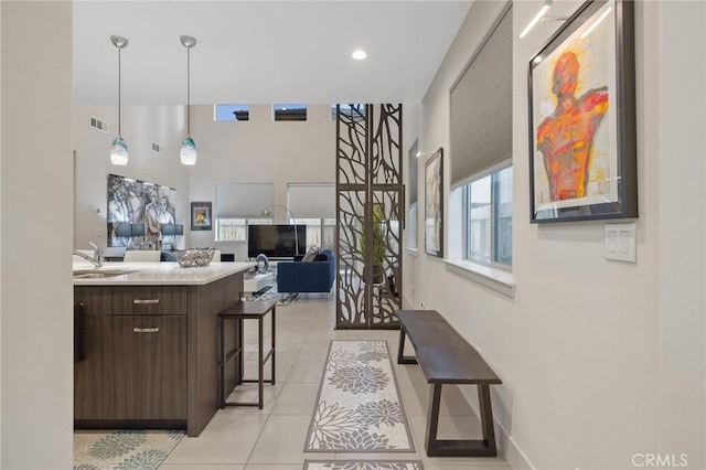 kitchen featuring dark brown cabinetry, light tile patterned floors, a kitchen breakfast bar, open floor plan, and light countertops