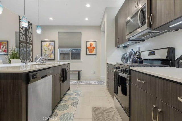 kitchen featuring dark brown cabinetry, stainless steel appliances, light countertops, a sink, and light tile patterned flooring