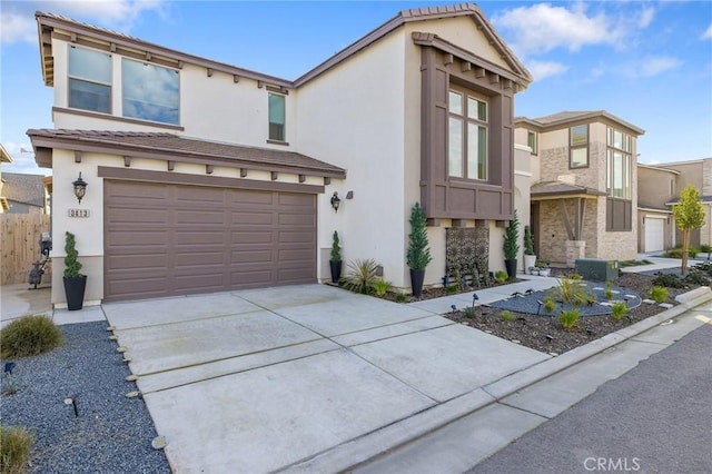 view of front of home featuring driveway, an attached garage, a tiled roof, and stucco siding