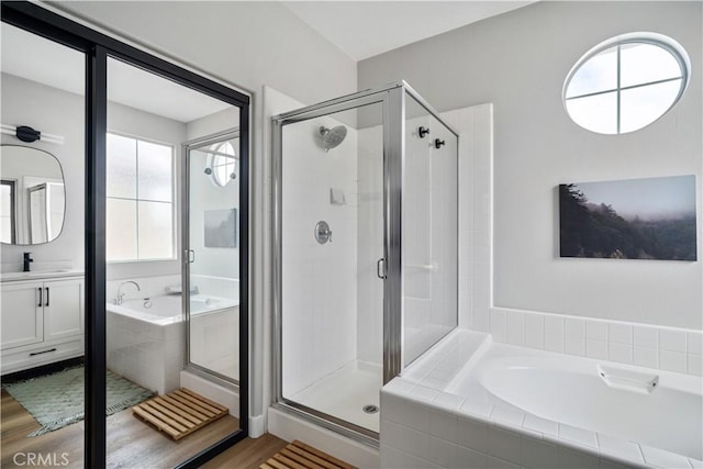 bathroom featuring a garden tub, a shower stall, a wealth of natural light, and wood finished floors