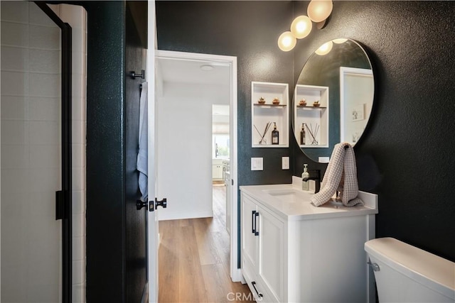 full bathroom featuring toilet, a shower with door, wood finished floors, and a textured wall