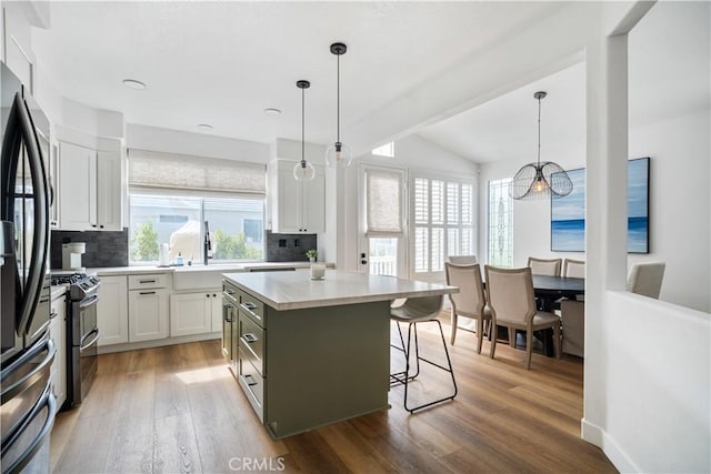 kitchen with a sink, white cabinets, light wood-style floors, fridge with ice dispenser, and backsplash