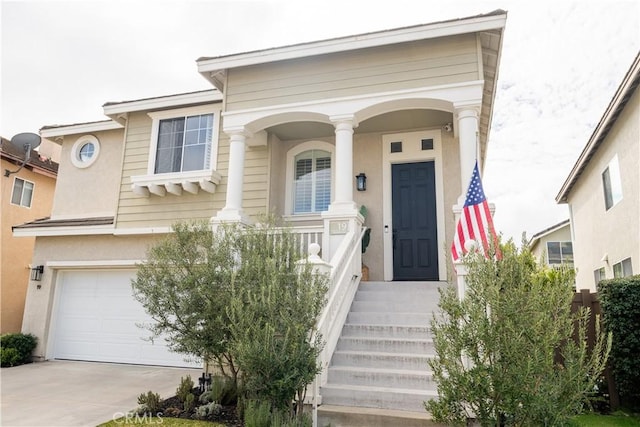 property entrance featuring concrete driveway, an attached garage, and stucco siding