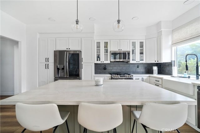 kitchen with white cabinetry, light countertops, appliances with stainless steel finishes, hanging light fixtures, and backsplash