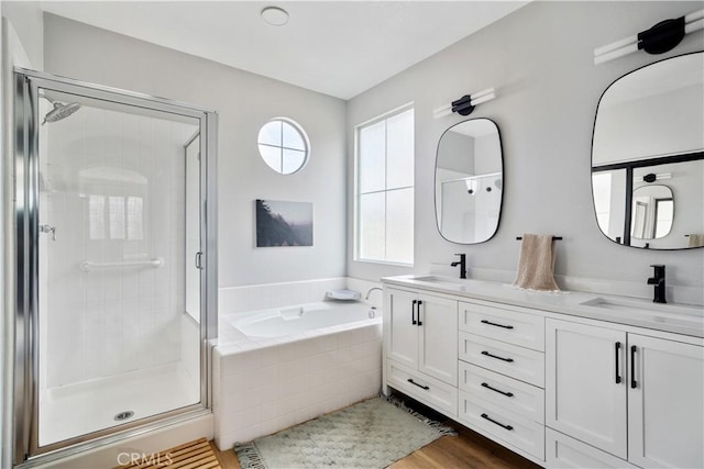 full bath featuring a bath, a stall shower, double vanity, and a sink