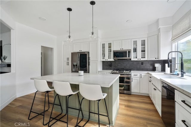 kitchen with light wood-style floors, appliances with stainless steel finishes, a kitchen breakfast bar, and a sink