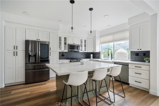 kitchen featuring a breakfast bar area, wood finished floors, white cabinets, appliances with stainless steel finishes, and a center island