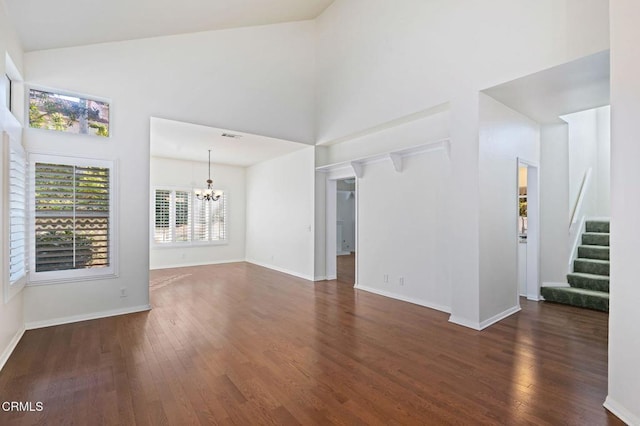 unfurnished living room featuring stairway, a chandelier, high vaulted ceiling, and wood finished floors