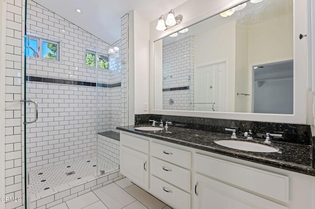 bathroom featuring a stall shower, tile patterned flooring, vaulted ceiling, and a sink