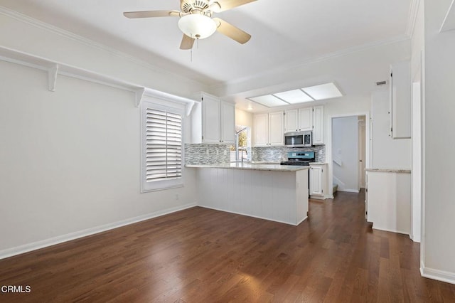 kitchen with a peninsula, white cabinets, light countertops, appliances with stainless steel finishes, and decorative backsplash