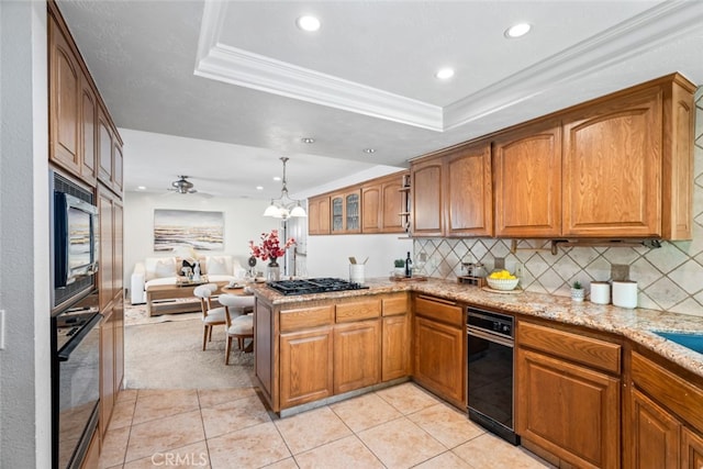 kitchen with a peninsula, open floor plan, brown cabinets, black appliances, and a tray ceiling