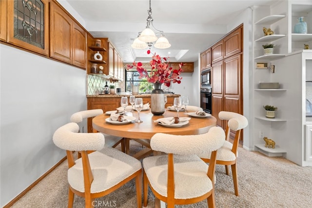 dining space featuring baseboards, a raised ceiling, and light colored carpet