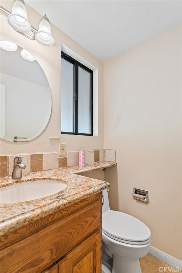 half bath featuring toilet, tile patterned floors, baseboards, and vanity