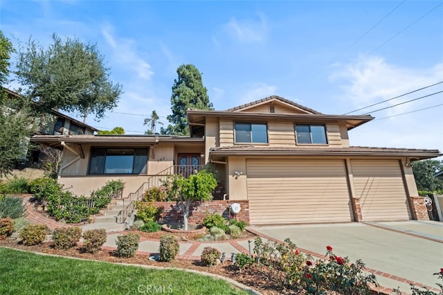 view of front facade with an attached garage, a tiled roof, concrete driveway, and stucco siding