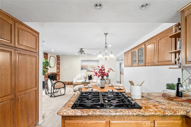 kitchen with carpet, cooktop, a fireplace, and light stone countertops