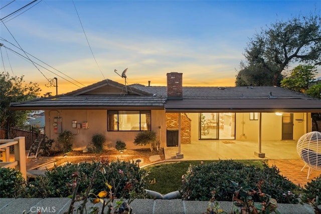 rear view of property featuring a patio, a chimney, and stucco siding