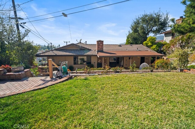 rear view of house with a lawn, a chimney, and a patio