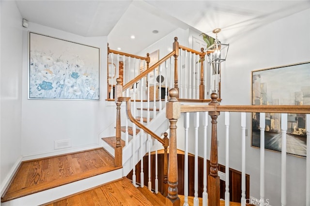 staircase with a chandelier, wood finished floors, and visible vents