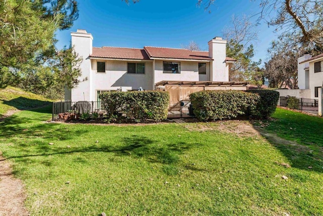 back of house featuring a tile roof, a yard, a chimney, stucco siding, and fence