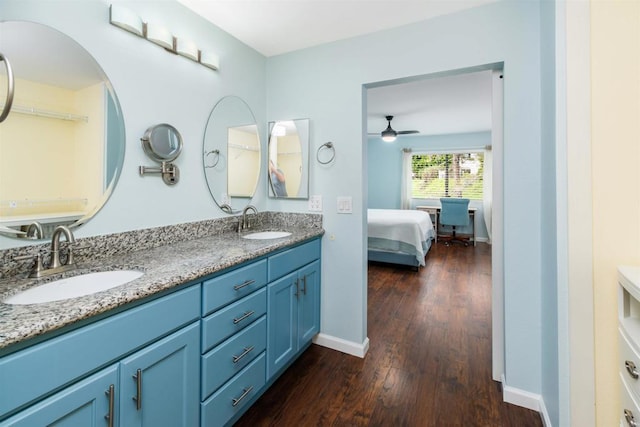 bathroom featuring double vanity, a sink, baseboards, and wood finished floors