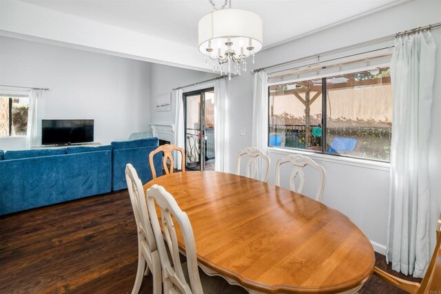 dining area with a chandelier, dark wood-type flooring, and a fireplace