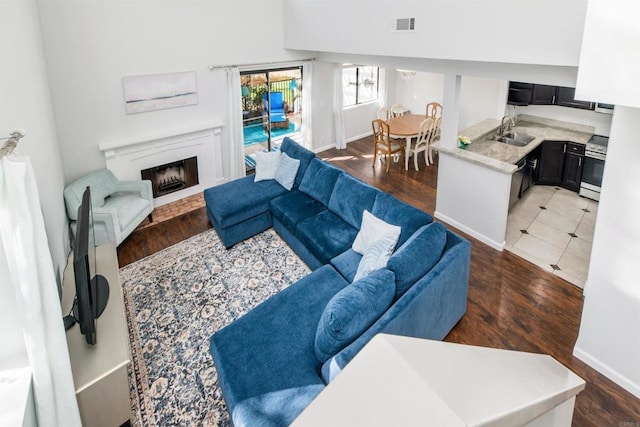 living area with a fireplace with flush hearth, wood finished floors, visible vents, and baseboards