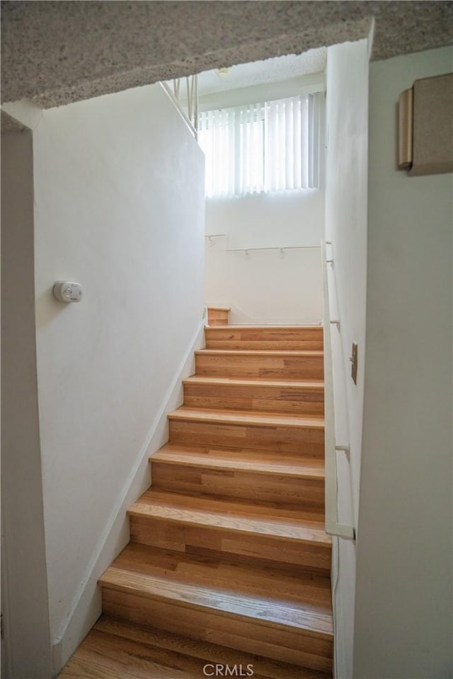 stairway featuring wood finished floors and baseboards