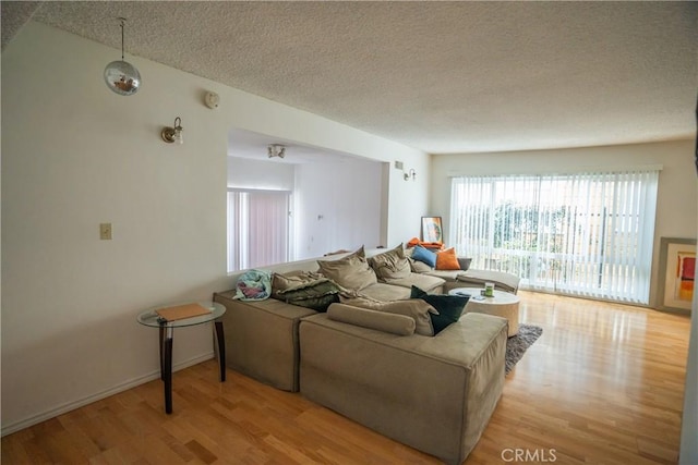 living room featuring light wood-type flooring and a textured ceiling