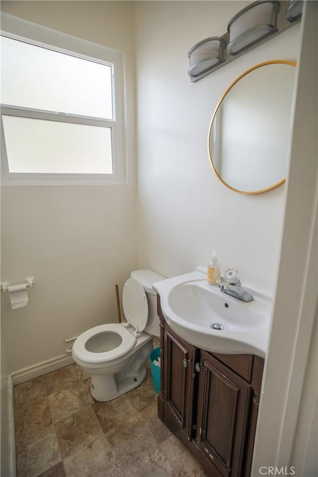 bathroom with toilet, baseboards, and vanity