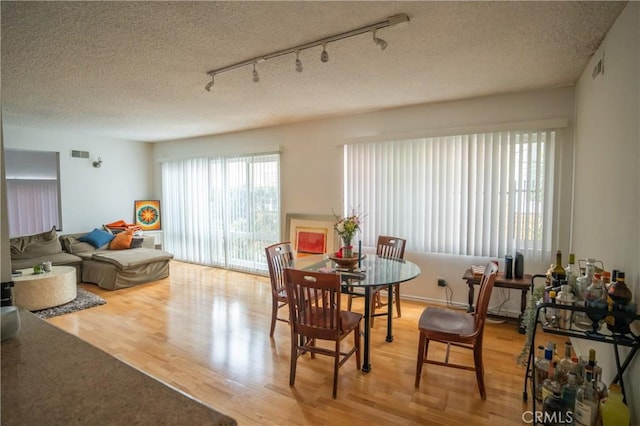 dining area with a textured ceiling, wood finished floors, and visible vents