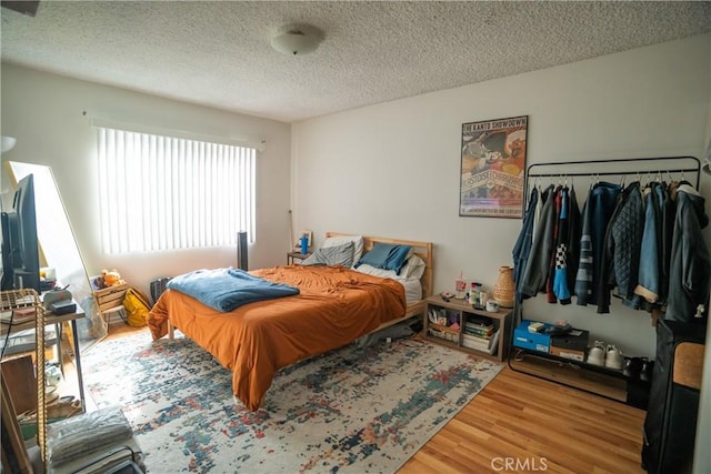 bedroom with a textured ceiling and wood finished floors