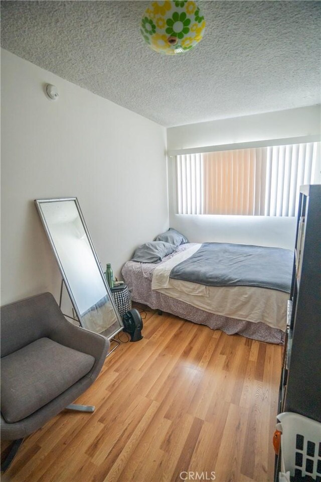 bedroom with wood finished floors and a textured ceiling