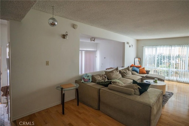 living room with a textured ceiling, wood finished floors, and baseboards