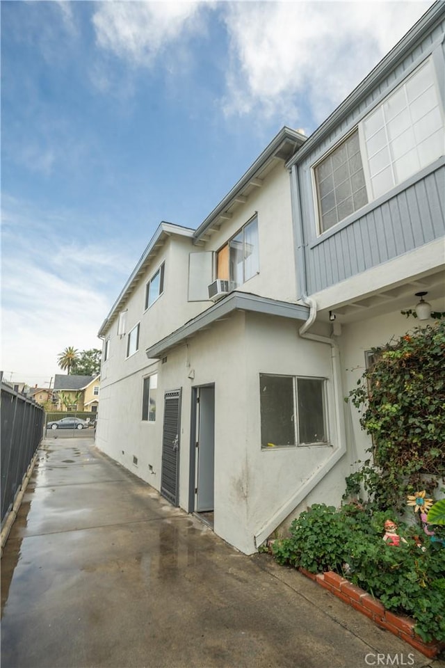 view of side of home with fence and stucco siding