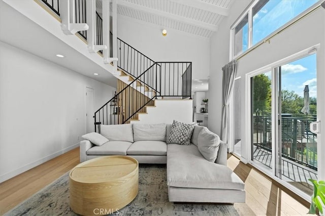 living room featuring stairway, wood finished floors, high vaulted ceiling, beamed ceiling, and baseboards