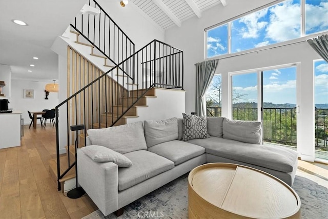 living area featuring recessed lighting, high vaulted ceiling, beamed ceiling, hardwood / wood-style floors, and stairs