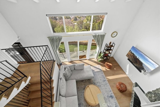 living room with stairway, wood finished floors, and a towering ceiling