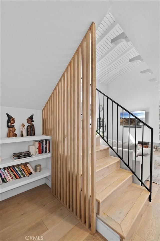 stairs with wood ceiling, lofted ceiling with beams, and wood finished floors