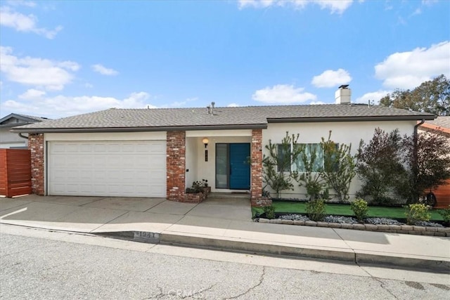 view of front facade with an attached garage, fence, concrete driveway, stucco siding, and a chimney